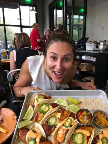 A woman looks excitedly at a platter of fish tacos at the Mas Taco Bar